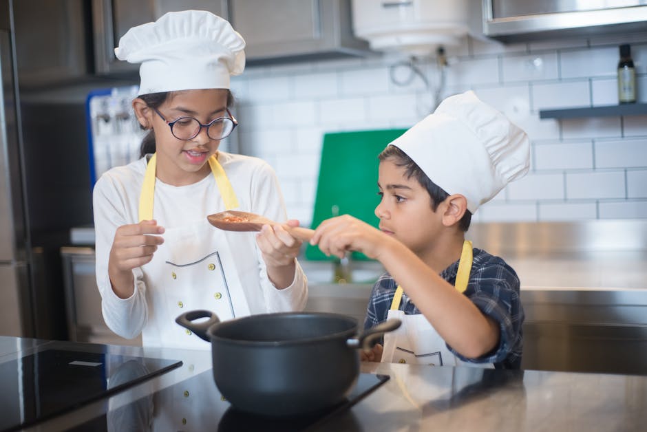 Two young children in chef hats cooking together in a modern kitchen setting. (Photo : Kampus Production / Pexels)